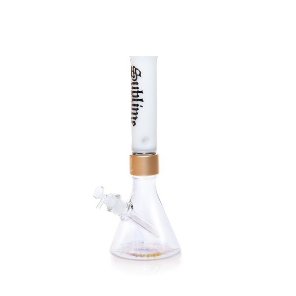 A fully assembled Prism x Sublime official clear glass modular beaker bong. The transparent design offers a clean look, showcasing the gold Halo Connector and the iconic yellow sun logo on the base. The clear glass mouthpiece features the black Sublime gothic logo, emphasizing the "Long Beach, California" roots of the band.
